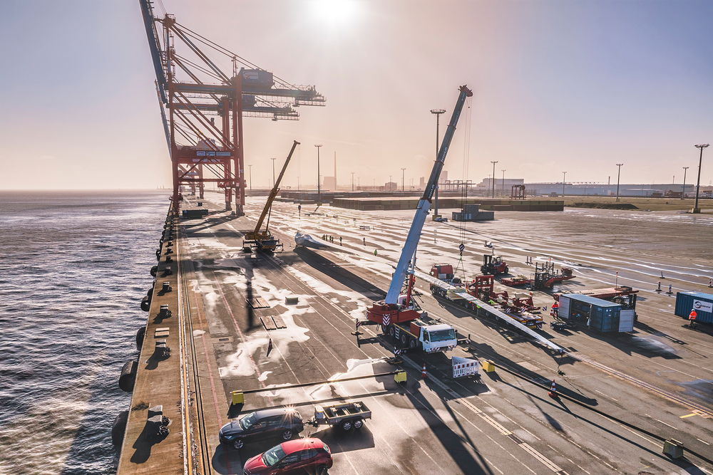 Schwertransport von Windradflügeln mit Kränen am Hafen bei Sonnenuntergang